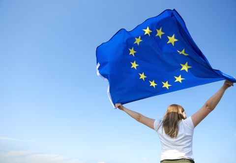 Girl flying the EU flag against a blue sky