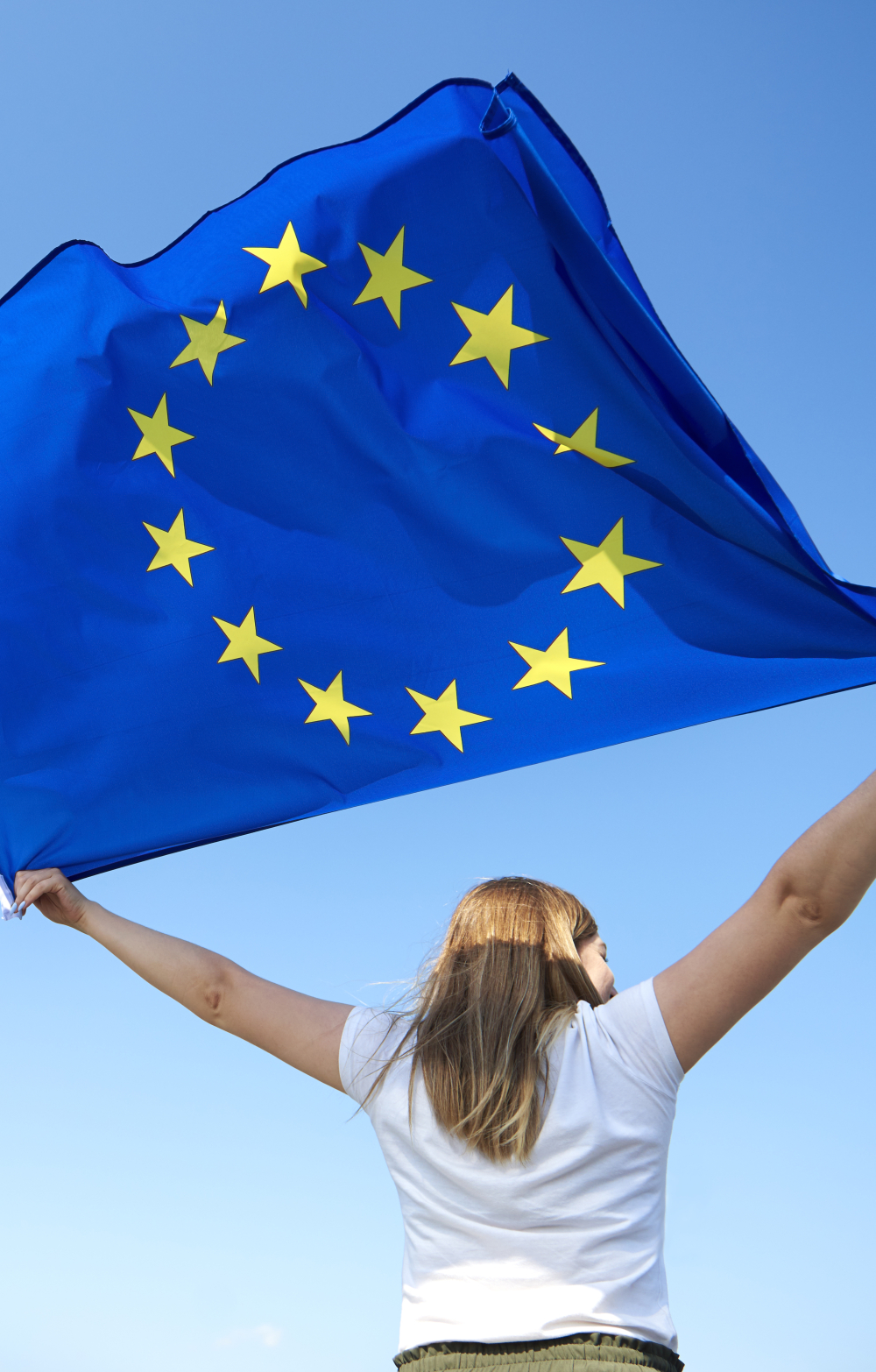 Girl flying the EU flag against a blue sky