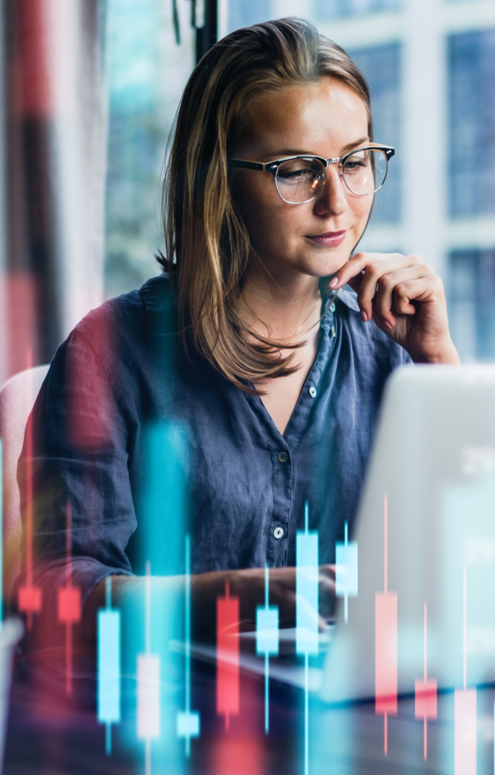 Lady wearing glasses in a blue blouse looking pensively at her laptop screen