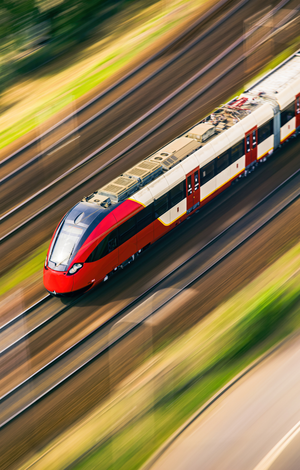 Fast red and white train entering town an aerial view