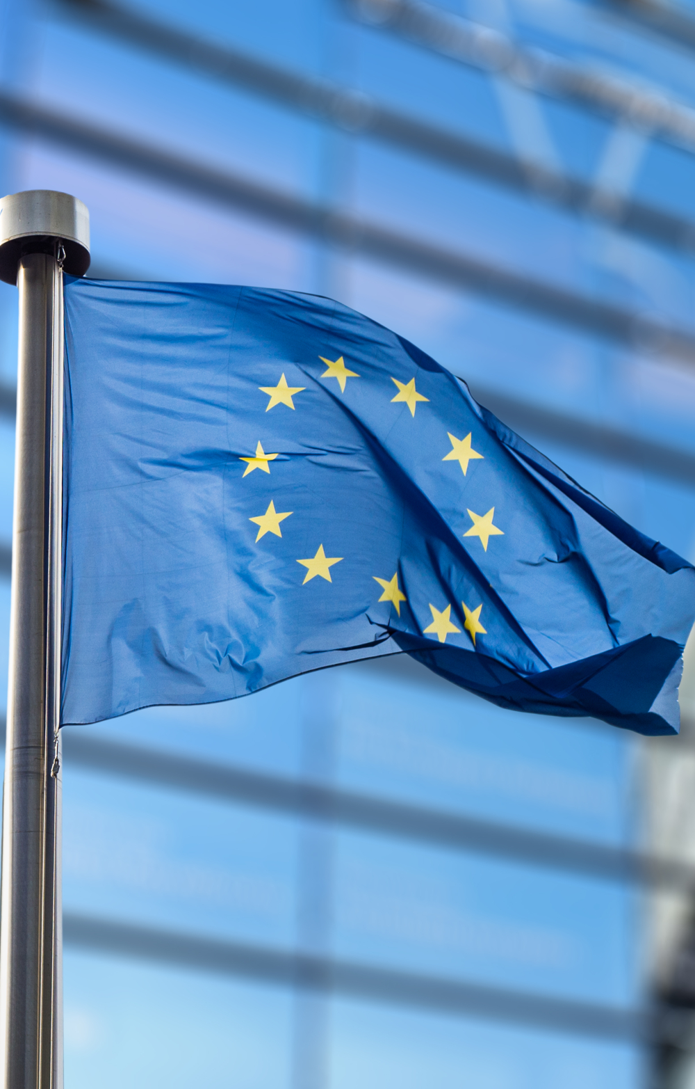 European Union Flag flying full mast against background of EU building